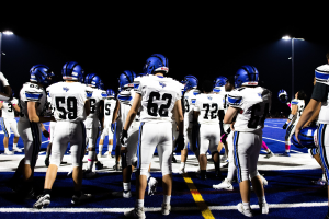 Gruppe von Fußballspielern in Helmen und Stiefeln auf einem Feld unter Stadionbeleuchtung.