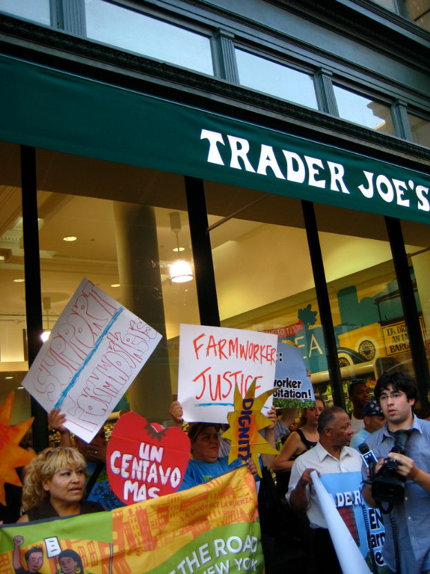 Eine Gruppe von Menschen steht in der Nähe eines Ladens und hält Schilder und Plakate in den Händen.