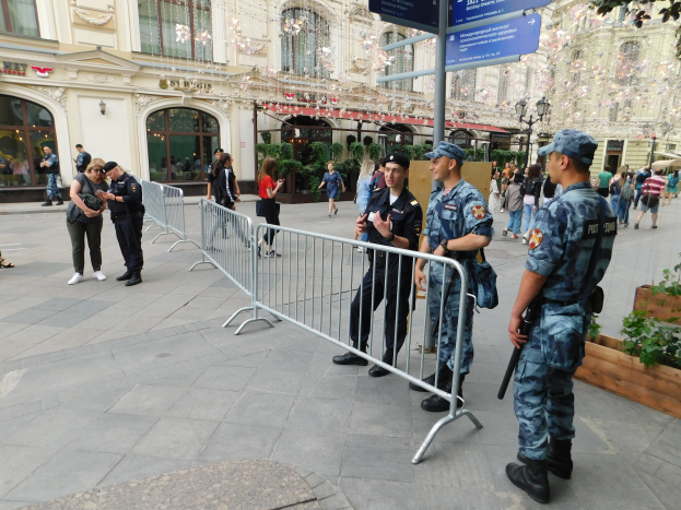 Eine Gruppe von Polizisten steht vor einer Menge, einige halten Waffen, mit Barrikaden und Schildern im Vordergrund und Gebäuden, Laternenmasten, Pflanzen und Bäumen im Hintergrund in Wien, Österreich während einer Anti-Terror-Operation.
