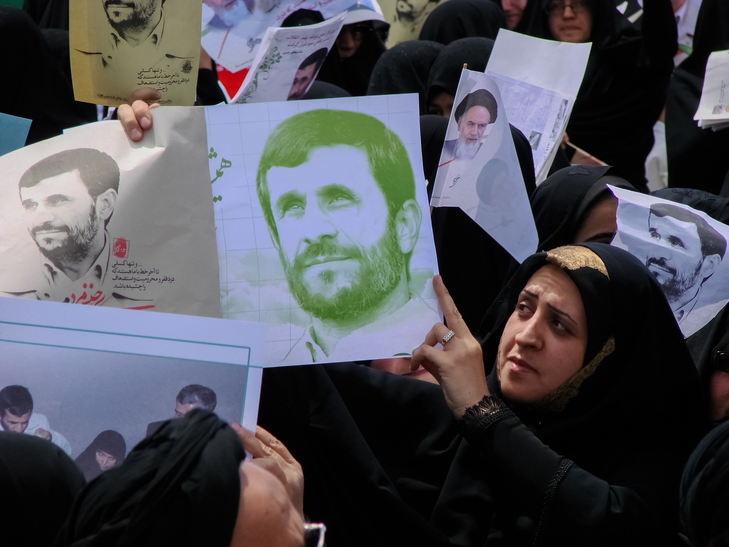 Eine Gruppe iranischer Frauen in schwarzer Kleidung, einige mit Brille, halten Bilder von Präsident Mahmoud Ahmadinejad während einer Kundgebung in Teheran.