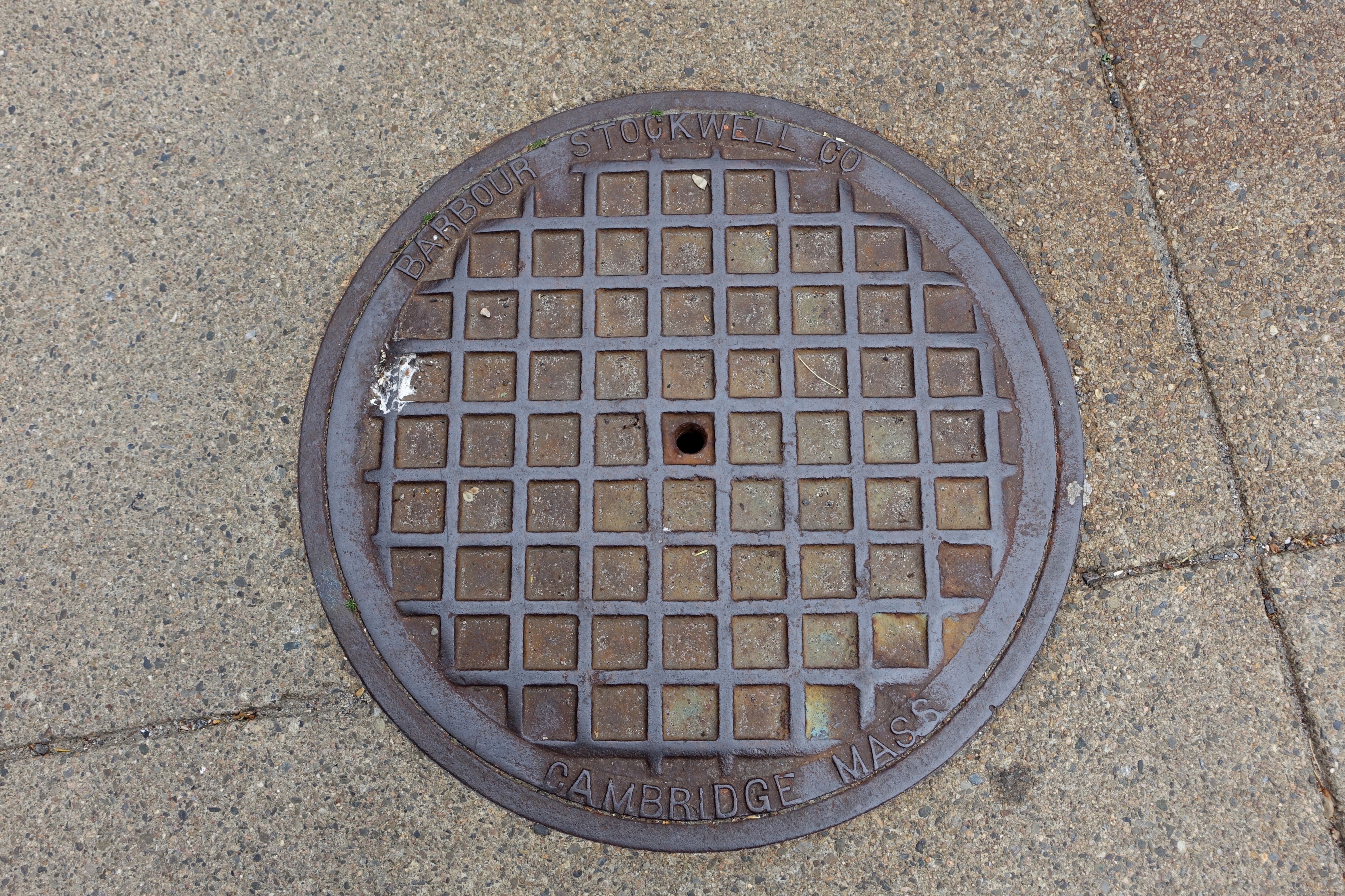 Ein rundes Metallgullideckel auf einem Stadtsteig mit eingravierter Schrift.