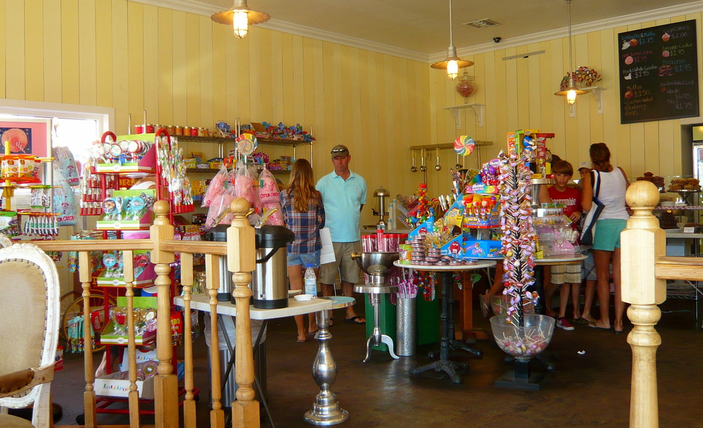 Eine Gruppe von Menschen, die vor einem Geschäft mit Süßigkeiten, Bonbons und Backwaren stehen.